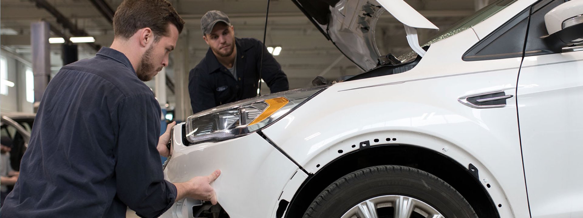 Collision technicians inspecting a Ford vehicle
